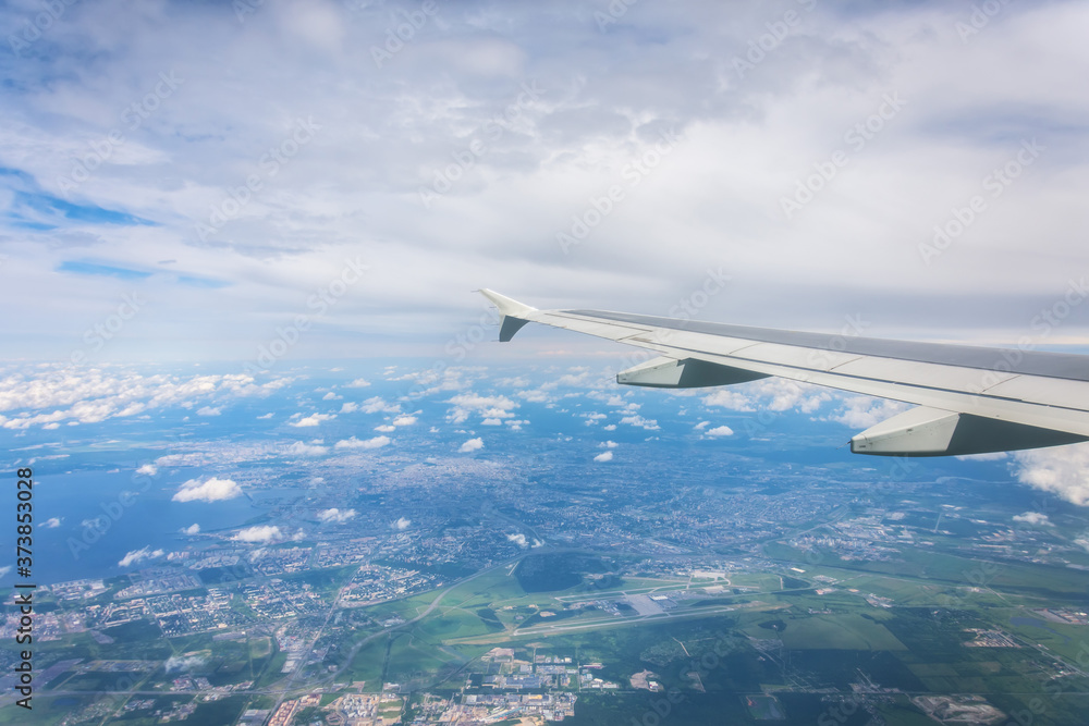 Porthole view of the wing and the big city with the airport.