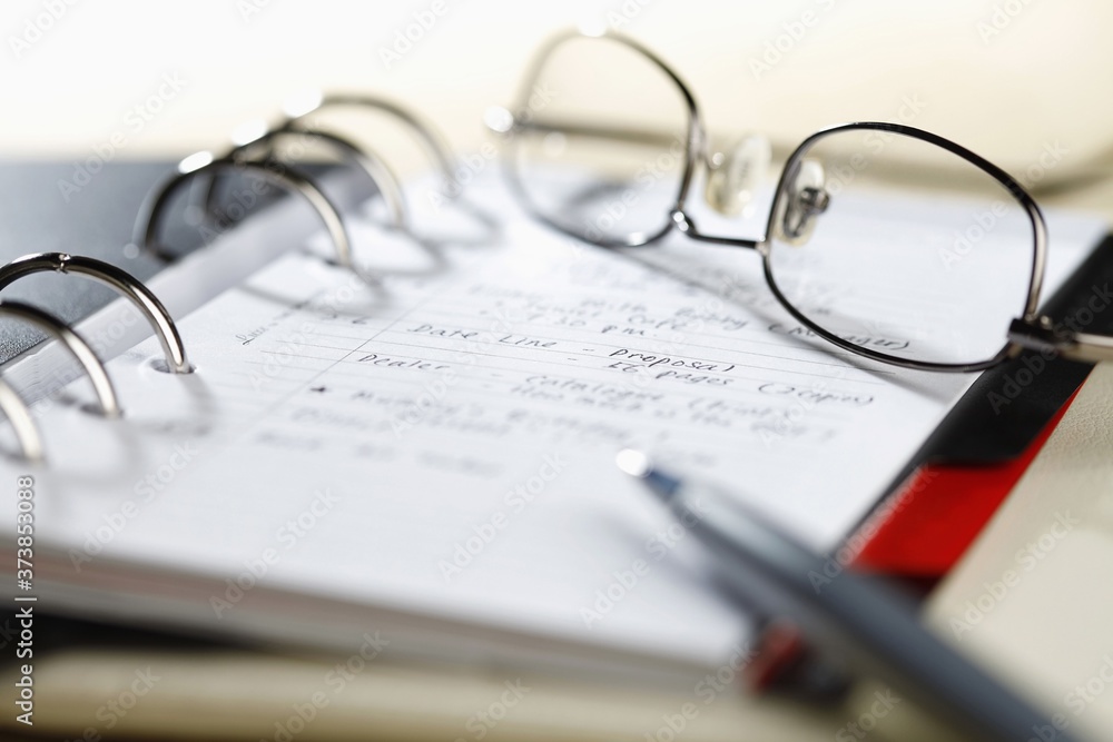 Close-up of organizer with glasses and pen Close-up of organizer with glasses and pen