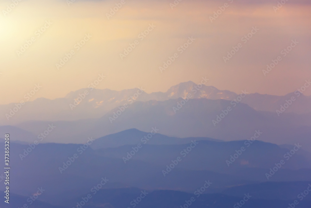 Silhouettes of snow mountains by the sea in the evening light with haze in the atmosphere. Silhouettes of snow mountains by the sea in the evening light with haze in the atmosphere.