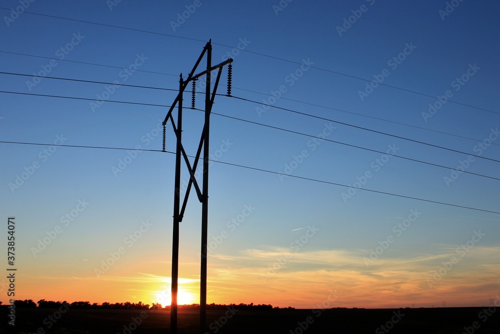 Kansas colorful Sunset with clouds and sky with power lines and poles silhouettes