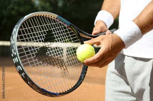 Sportsman preparing to serve tennis ball at court, closeup © New Africa