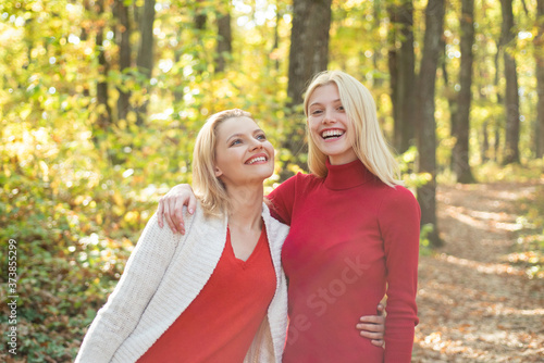 Two girls outdoors enjoying nature. Autumn female models, fashion portrait women on maple leaves. Friends people concept.
