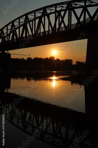 The reflection of the old bridge on the river,The silhouette of the old bridge at sunrise or sunset in the countryside © michaelmonzer