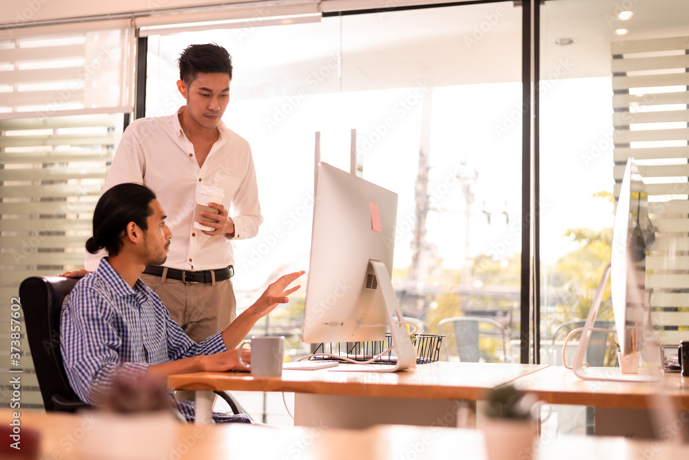 Two office worker discussing business on desktop computer Two office worker discussing business on desktop computer