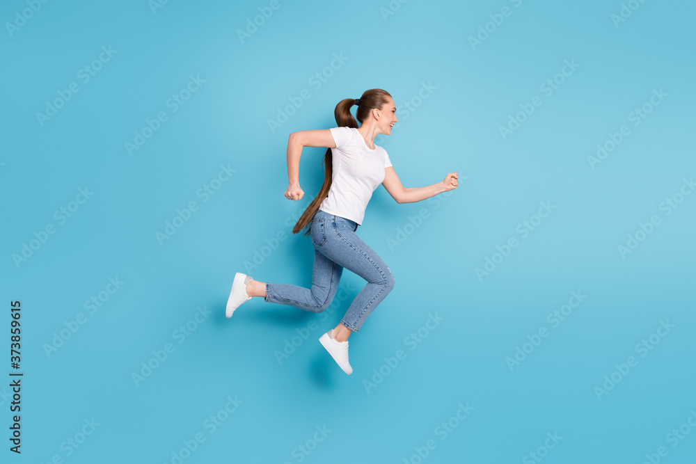 Full body profile side photo of excited girl listen incredible season discounts jump run copyspace wear good look clothes gumshoes isolated over blue color background