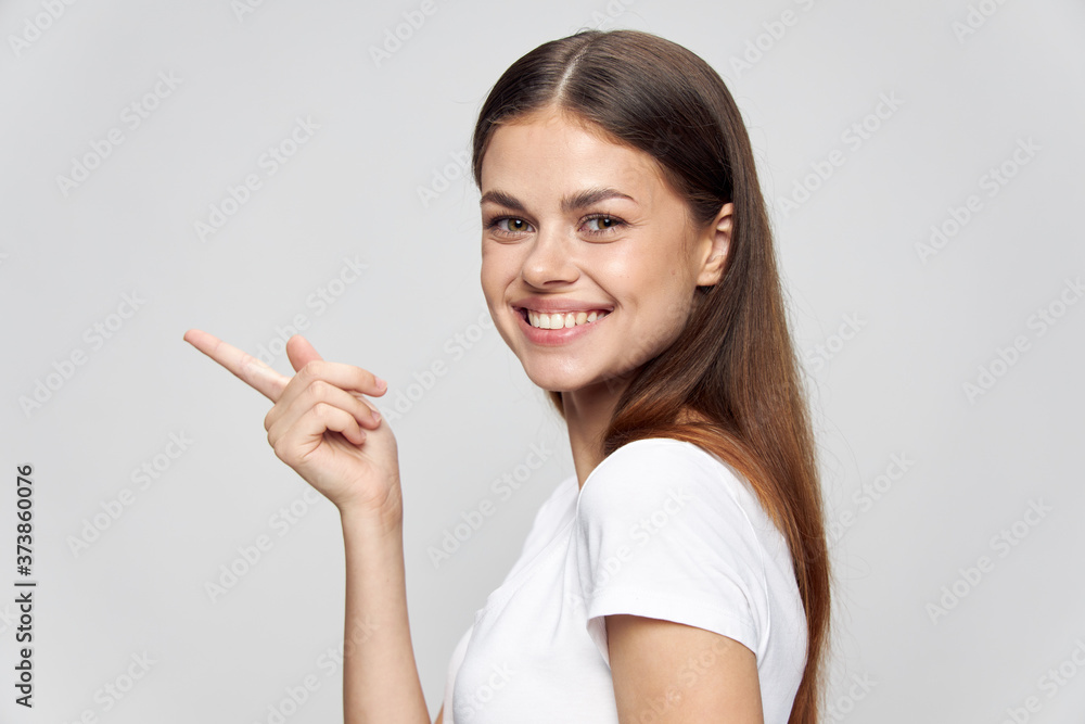 happy girl shows a finger to the sides in a white t-shirt on an isolated background happy girl shows a finger to the sides in a white t-shirt on an isolated background