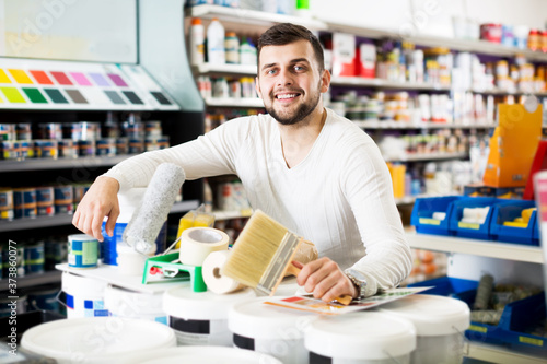Happy male customer purchasing tools for house improvements in paint supplies store