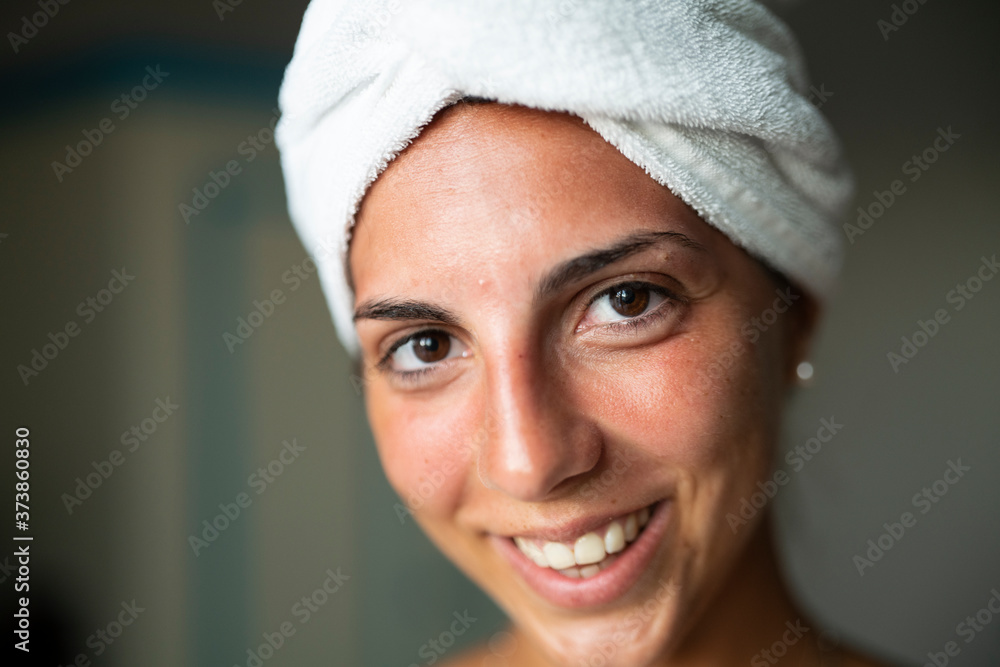 Close up of an young happy woman with towel on her head and face just cleaned from impurities is ready for day or night cream is smiling in camera in a bathroom. Close up of an young happy woman with towel on her head and face just cleaned from impurities is ready for day or night cream is smiling in camera in a bathroom.