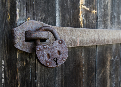 old hanging rusty iron lock on wooden door	