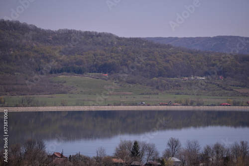 a lake in the village in spring season mirroring the big forest