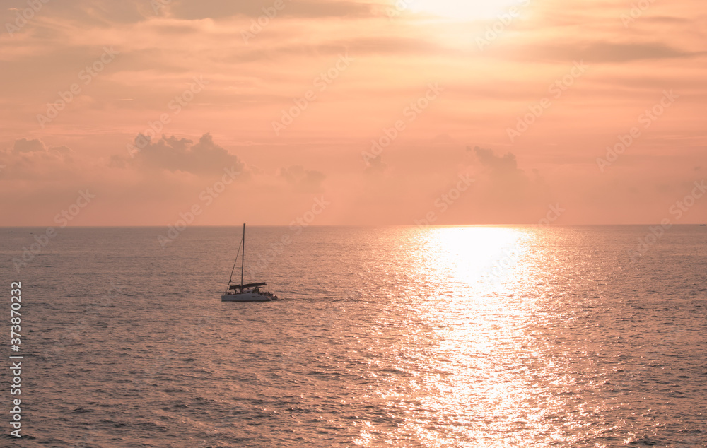 A sailboat playing in the sea at sunset