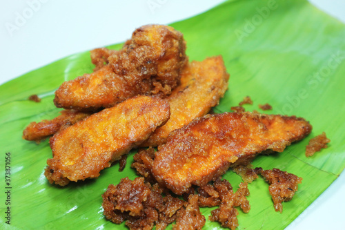 Fried banana fritters on banana leaf with white background