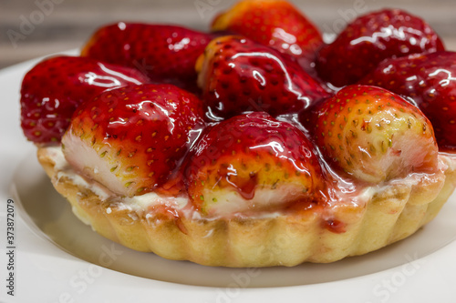 Mini strawberry cheese cake tart close up on white plate - fruity cheesecake background