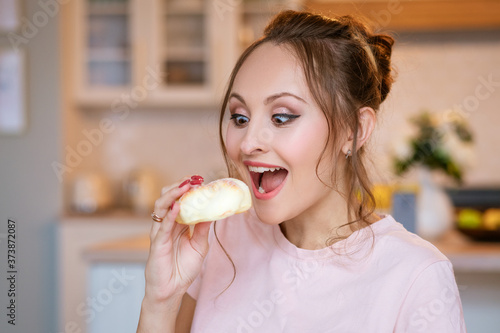 girl eating a white bun on the background of the kitchen