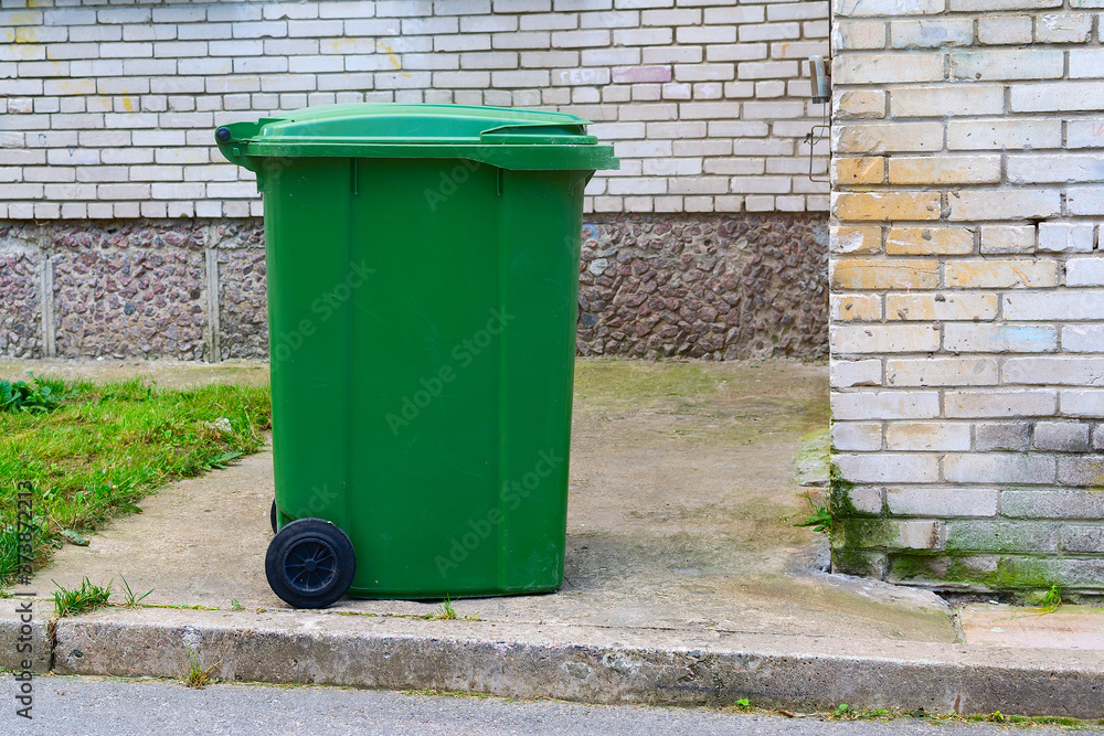 A green dumpster stands near the house A green dumpster stands near the house