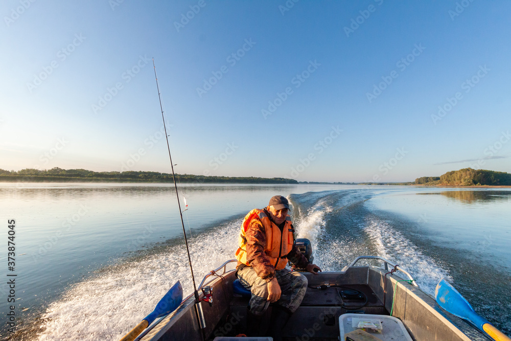 The fisherman floats on a fishing boat with a steering Tiller in Siberia, Middle of Russia during the summer