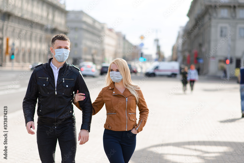 Young couple in love in protective medical mask on face outdoor at street. Environmental pollution concept. Guy and girl in virus protection Young couple in love in protective medical mask on face outdoor at street. Environmental pollution concept. Guy and girl in virus protection