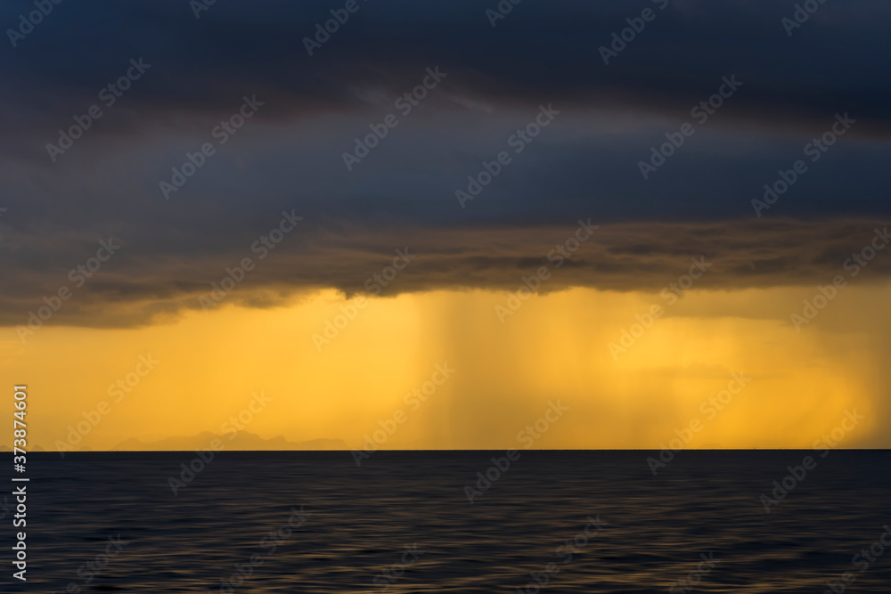 Seascape and rain clouds with sunlight in golden hour.