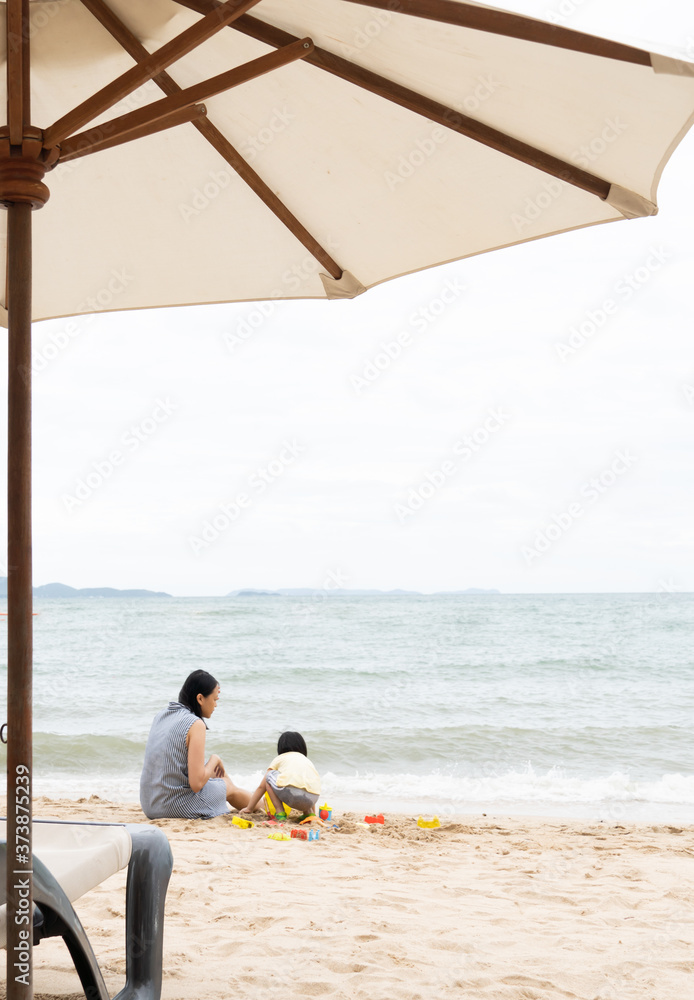 Mother and 3 years old asian kid play sand on the beach. Background for family life and education. holiday with children.