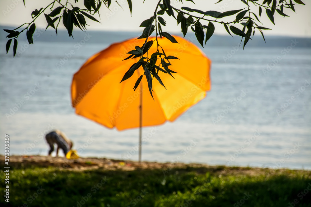 Yellow umbrella on the beach on the Minsk Sea last, 2019.