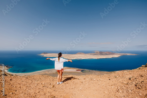 Happy traveller woman and scenic viewpoint to La Graciosa from Lanzarote
