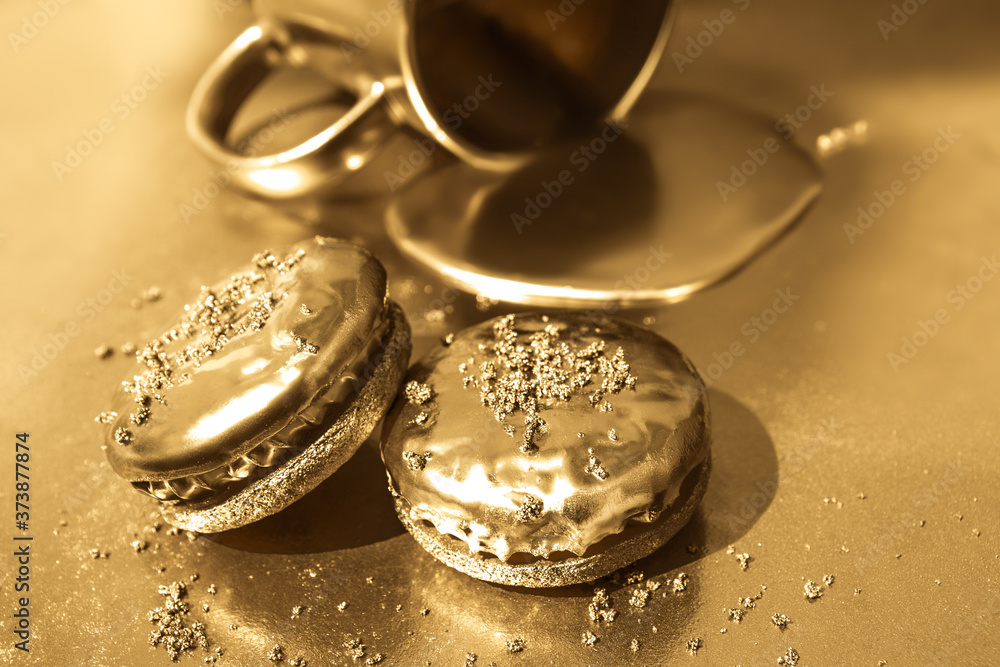Liquid gold flows from a golden cup. Golden cookies on a gold background. Liquid gold flows from a golden cup. Golden cookies on a gold background.