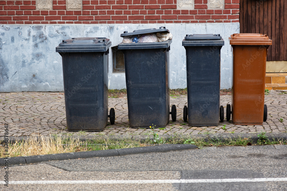 Garbage bins in different colors partly filled to overflowing as sign for an affluent society Garbage bins in different colors partly filled to overflowing as sign for an affluent society