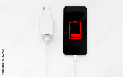 Discharged smartphone battery. Smartphone with battery level indicators and USB connection  next to a charger. Icon isolated on black phone and white background.