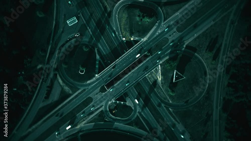 Dark night intersection, aerial spin hyperlapse. Traffic on highway cloverleaf junction interchange