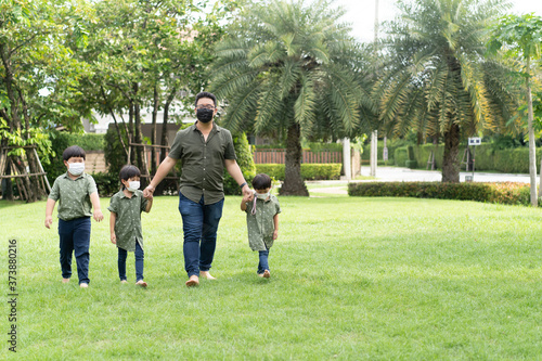 Father is walking in the garden with his 3 sons. © No-Te