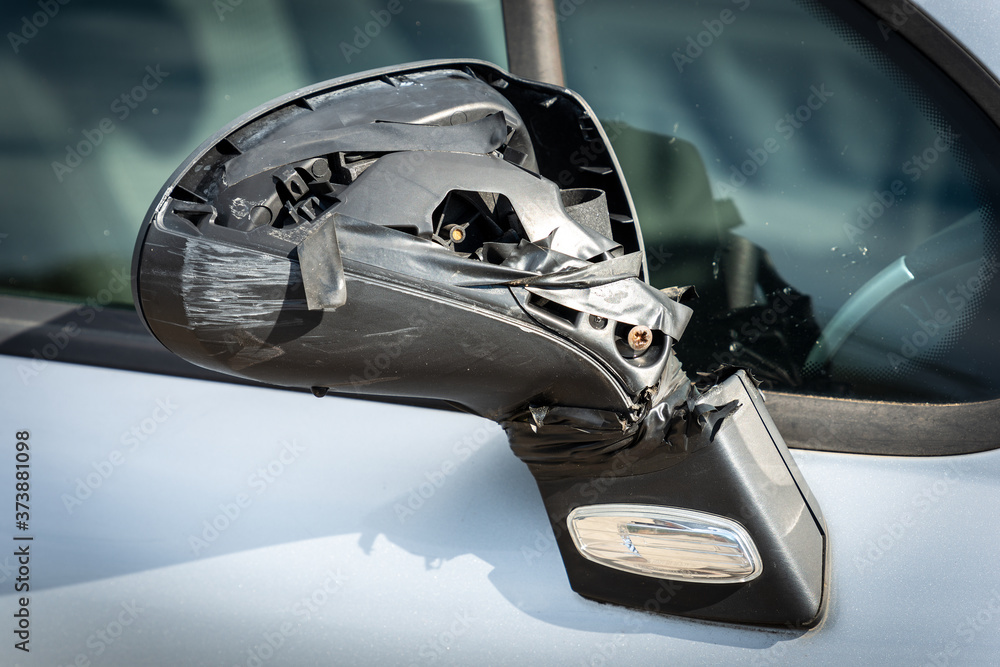 Closeup of a side broken rearview mirror of a car fixed with tape