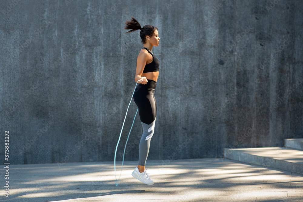 Fototapeta premium Side view of black girl exercising with skipping rope