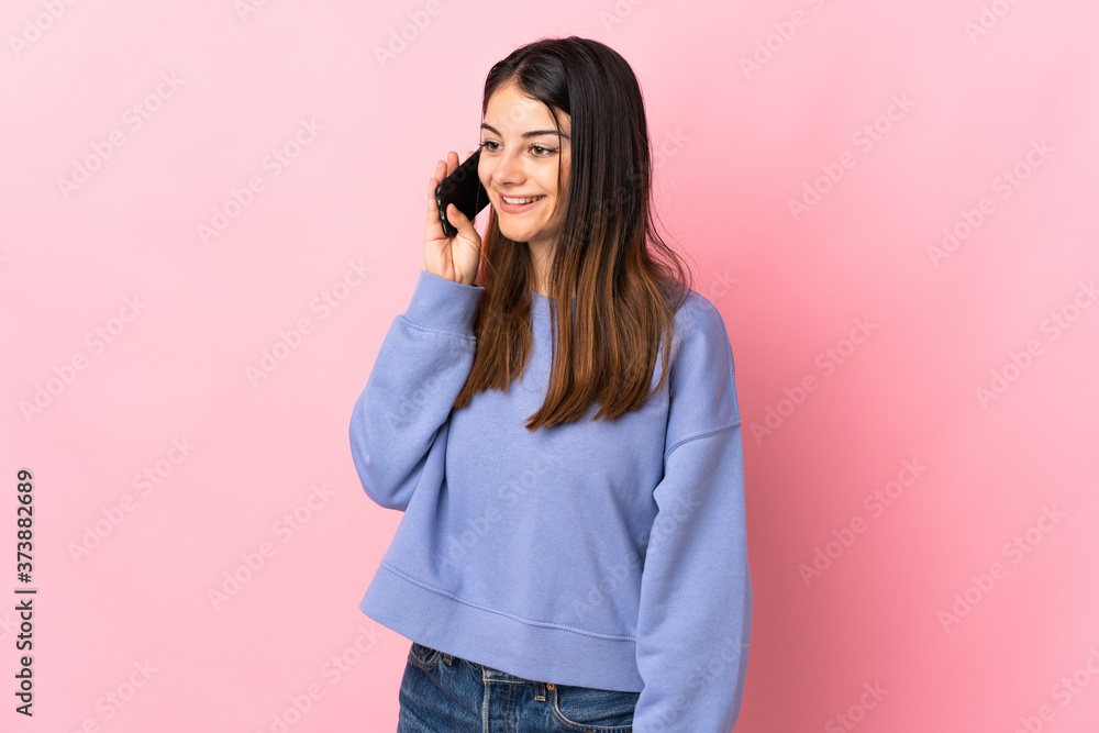 Young caucasian woman isolated on pink background keeping a conversation with the mobile phone Young caucasian woman isolated on pink background keeping a conversation with the mobile phone