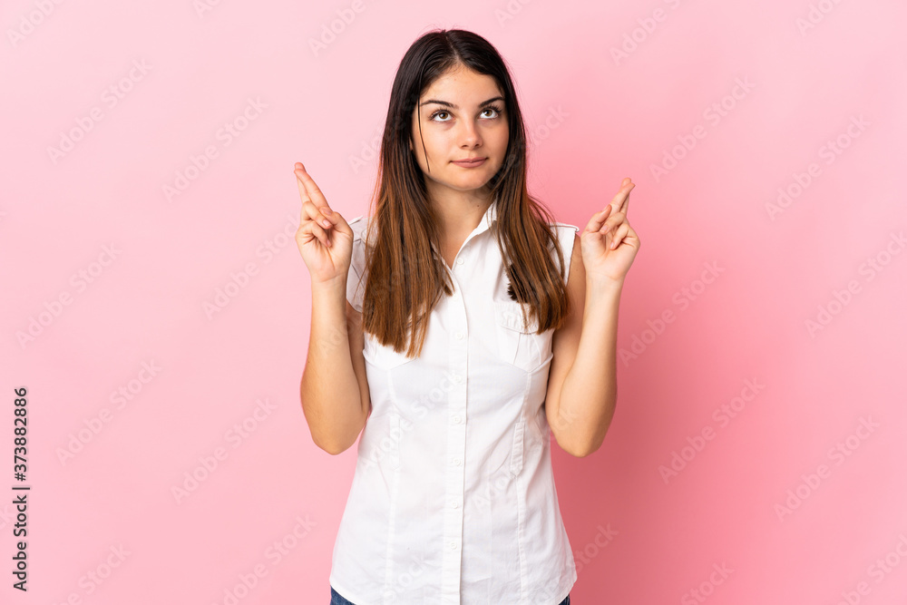 Young caucasian woman isolated on pink background with fingers crossing and wishing the best Young caucasian woman isolated on pink background with fingers crossing and wishing the best