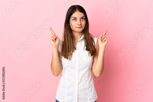 Young caucasian woman isolated on pink background with fingers crossing and wishing the best © luismolinero