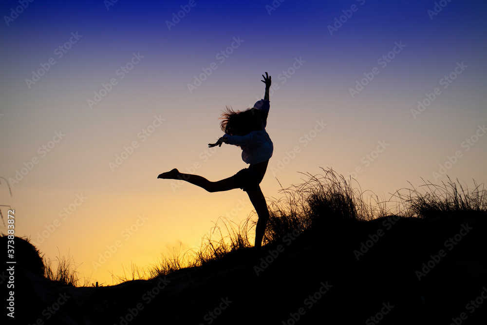 Silueta de chica saltando alegre en la puesta de sol