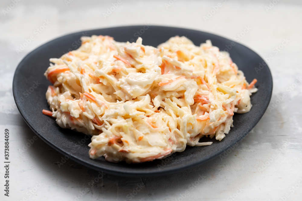 cabbage and carrot salad on dark plate on ceramic background cabbage and carrot salad on dark plate on ceramic background