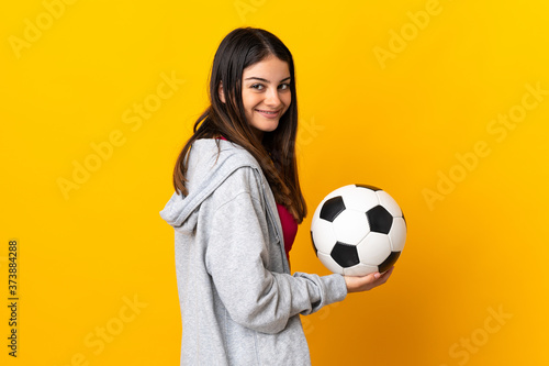 Young caucasian woman isolated on yellow background with soccer ball © luismolinero