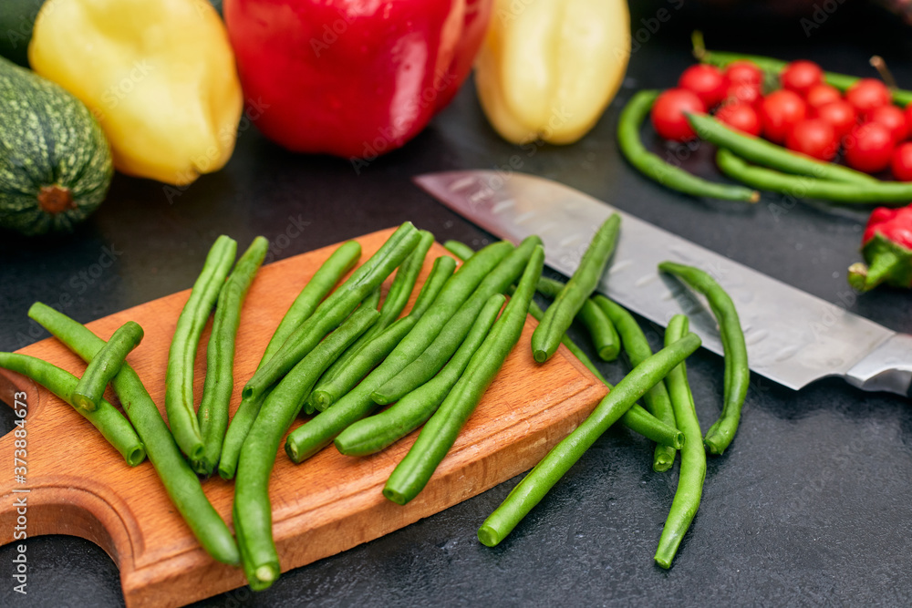 chopped green beans on a wood board with vegetables