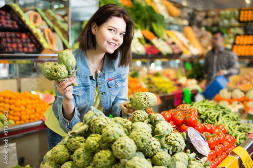 Young smiling woman choosing fruits in grocery shop © JackF