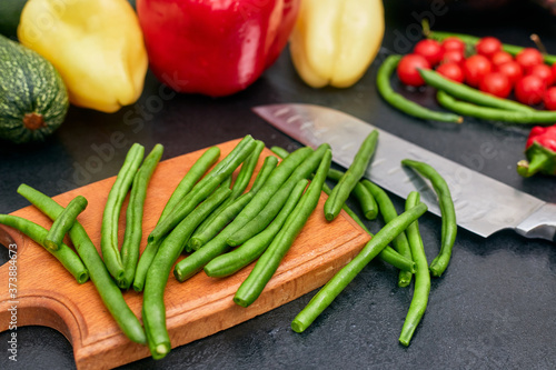 chopped green beans on a wood board with vegetables