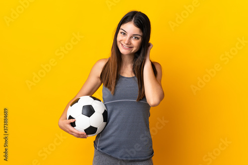 Young football player woman isolated on yellow background laughing © luismolinero