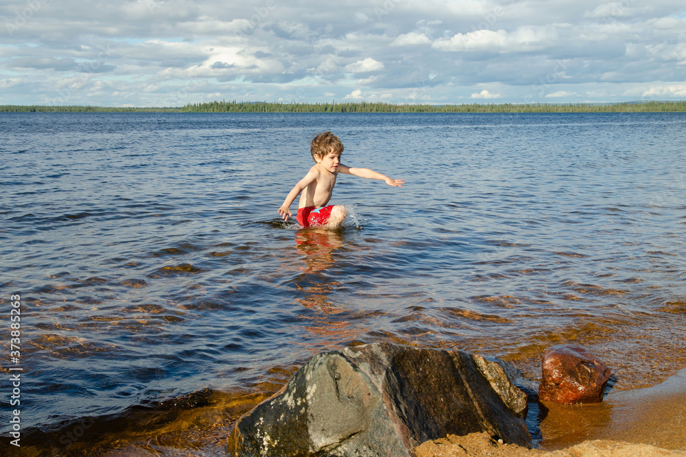 Boy hurries out of the cold water of Kanozero lake. Kola Peninsula, Murmansk Oblast, Russia. Boy hurries out of the cold water of Kanozero lake. Kola Peninsula, Murmansk Oblast, Russia.