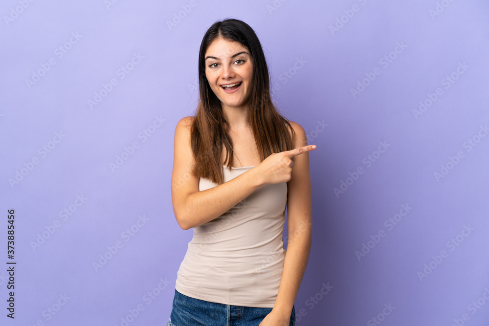 Young caucasian woman isolated on purple background surprised and pointing side Young caucasian woman isolated on purple background surprised and pointing side