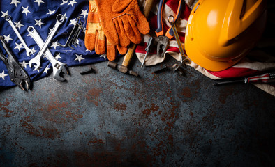 Happy Labor day concept. American flag with different construction tools on dark stone background, with copy space for text.