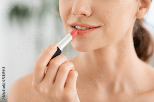 Closeup of young woman applying lipstick  copy space