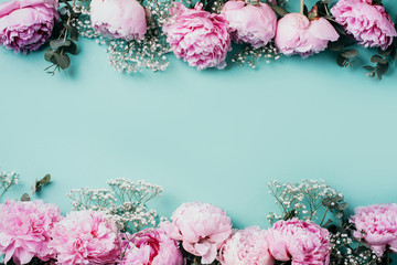 Creative frame pattern of pink peonies, gypsophila flowers, eucalyptus on blue background. Flat lay, top view. Floral composition. Wedding, birthday, anniversary bouquet. Woman day, Mother's day.