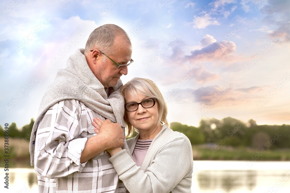 Old age, relationships and people concept - happy senior couple hugging in nature. The husband hugs his wife tenderly. Caring, love.Lifestyle 60 plus