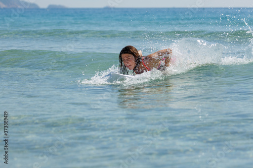 girl on a surfboard swims on the sea, summer, sunny day, clear water