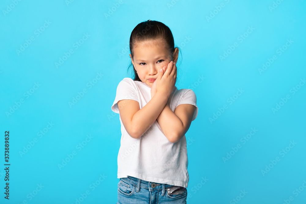 Adorable asian girl touching her cheek at studio Adorable asian girl touching her cheek at studio